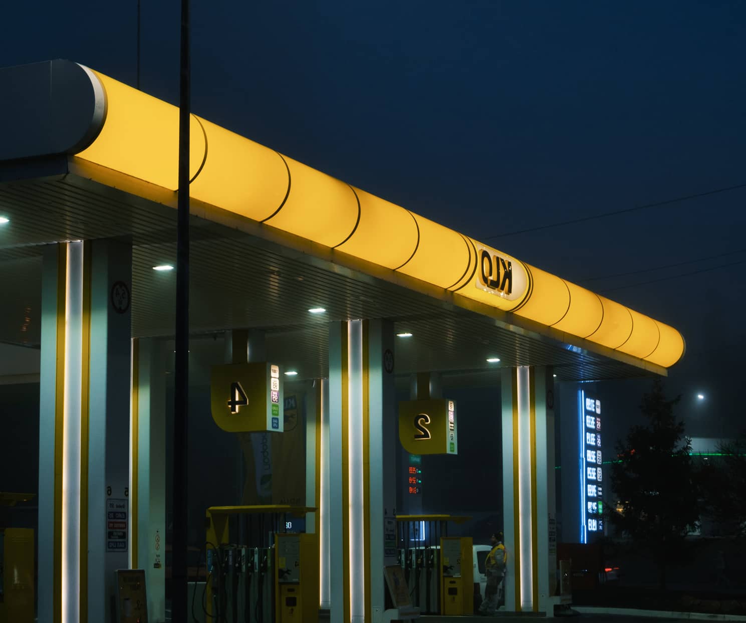 Station-service éclairée la nuit, symbolisant la garantie plancher comme un refuge protecteur pour le capital PER