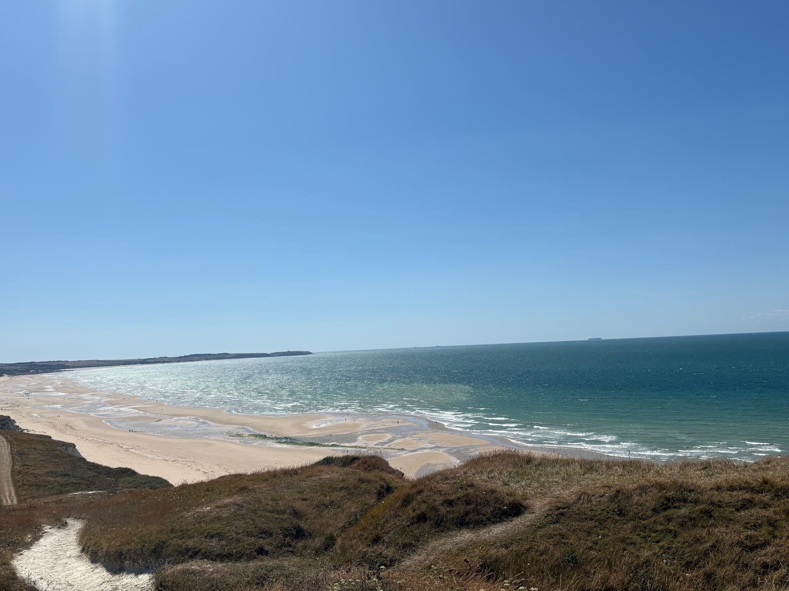 Vue panoramique sur une grande plage et la mer depuis les dunes, illustrant l'horizon long terme d'un PER alimenté régulièrement