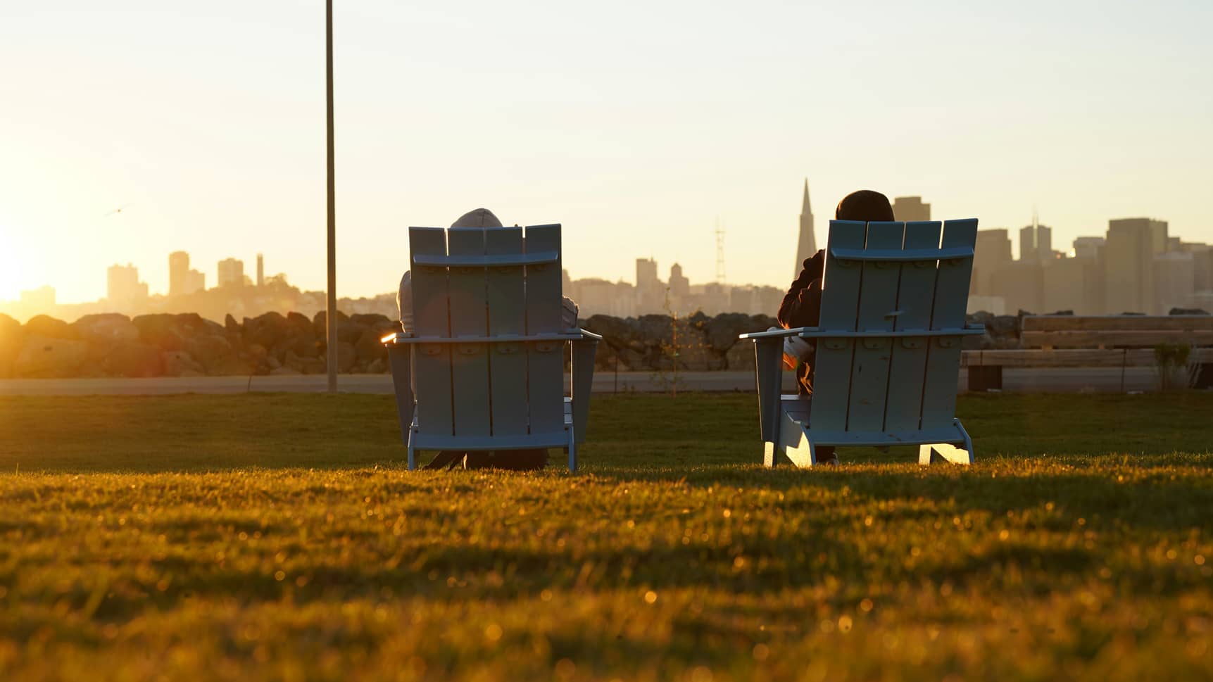 Deux fauteuils face à un coucher de soleil urbain, symbole de sérénité et de perspective à l'approche de la retraite