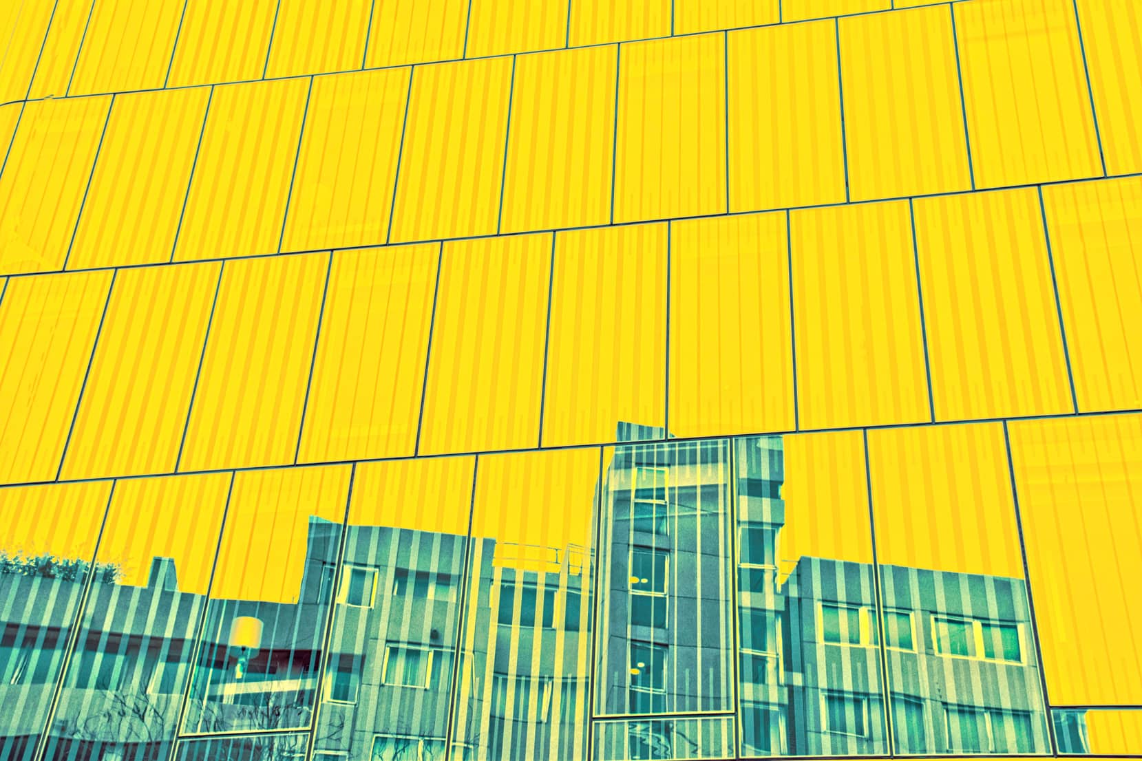 Façade contemporaine en panneaux jaunes et reflets de verre, symbole de structure et de transparence
