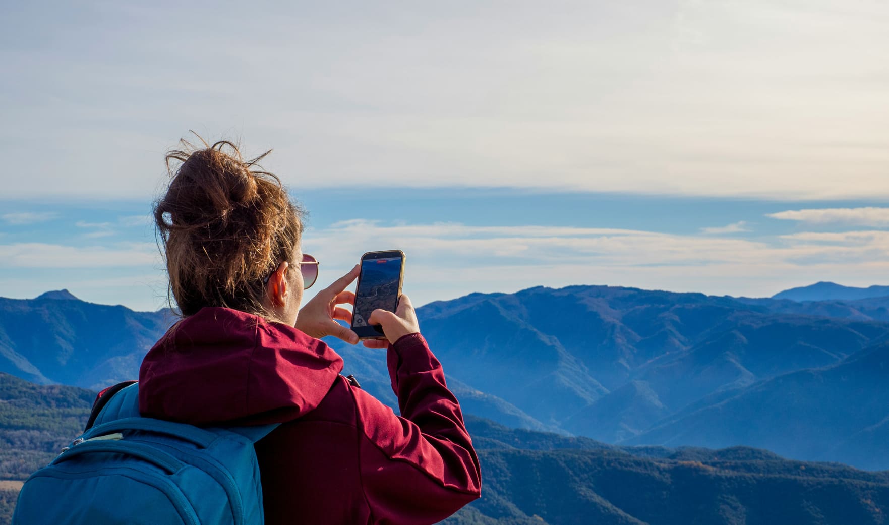 Randonneuse photographiant un panorama de montagnes, illustration de l'horizon long terme d'un PER